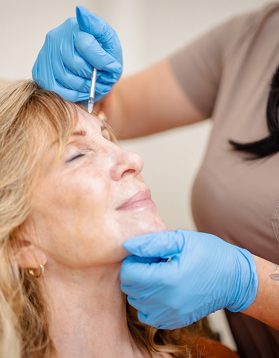 Administering cosmetic treatment to a smiling woman.